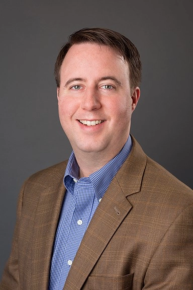 Rob Brockhaus, Vice President of Sales and Marketing at CMS, smiling in a professional headshot, wearing a brown blazer over a blue shirt, reflecting leadership in political campaign strategies and organizational growth.