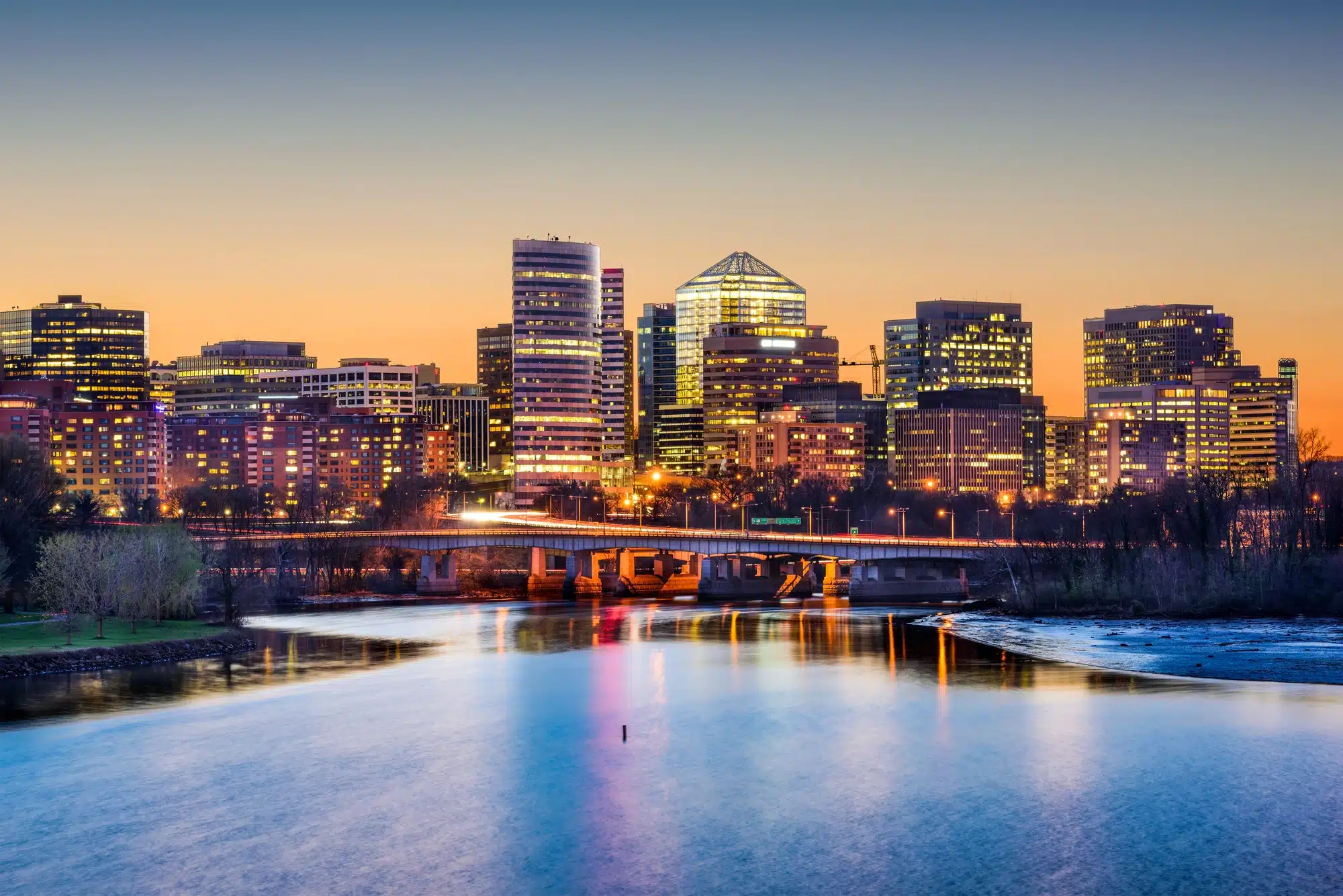 Arlington, Virginia skyline at dusk with illuminated buildings, reflecting in the water, showcasing the vibrant urban landscape relevant to CMS's strategic marketing focus.