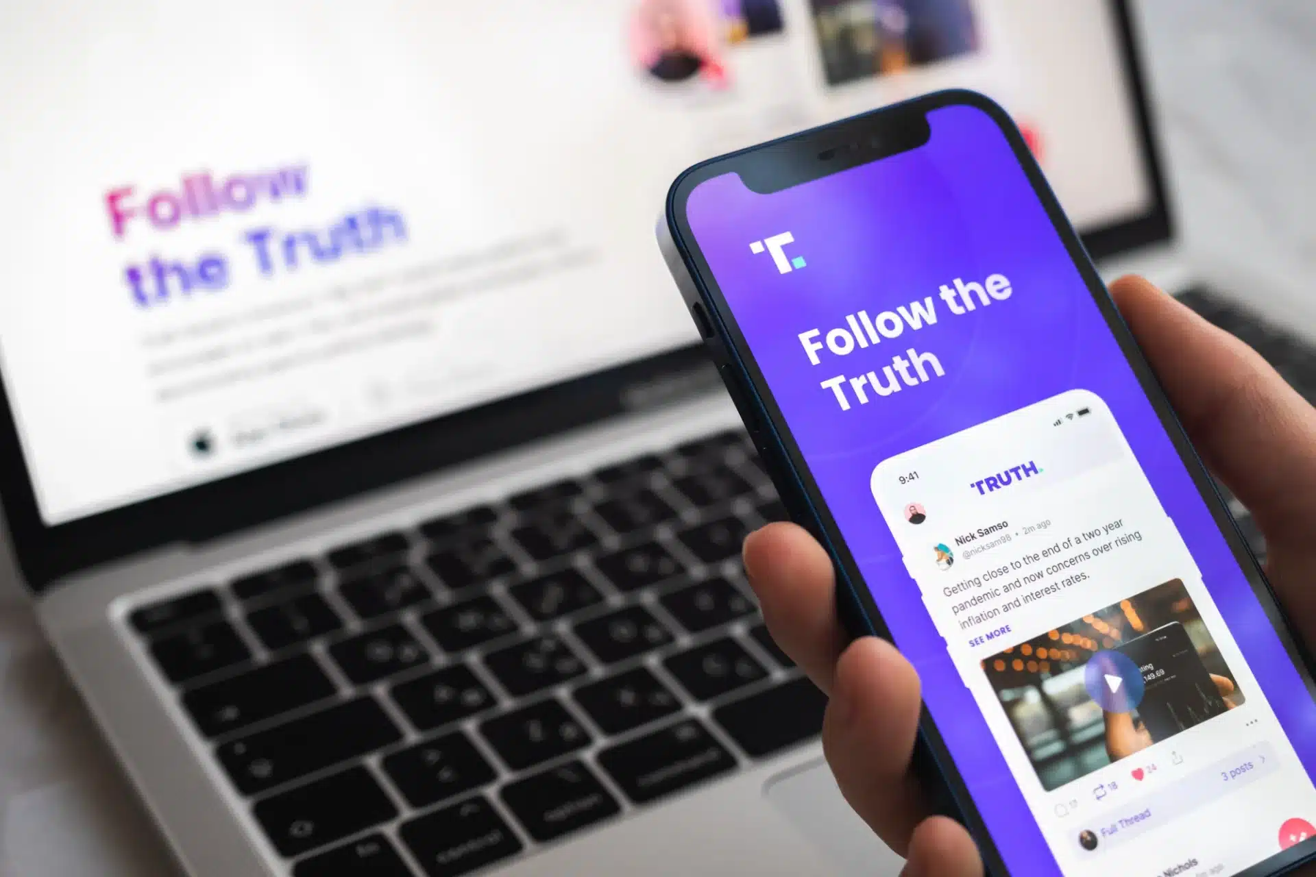 Smartphone displaying "Follow the Truth" app interface with social media posts, in front of a laptop, emphasizing digital engagement in political campaigns.